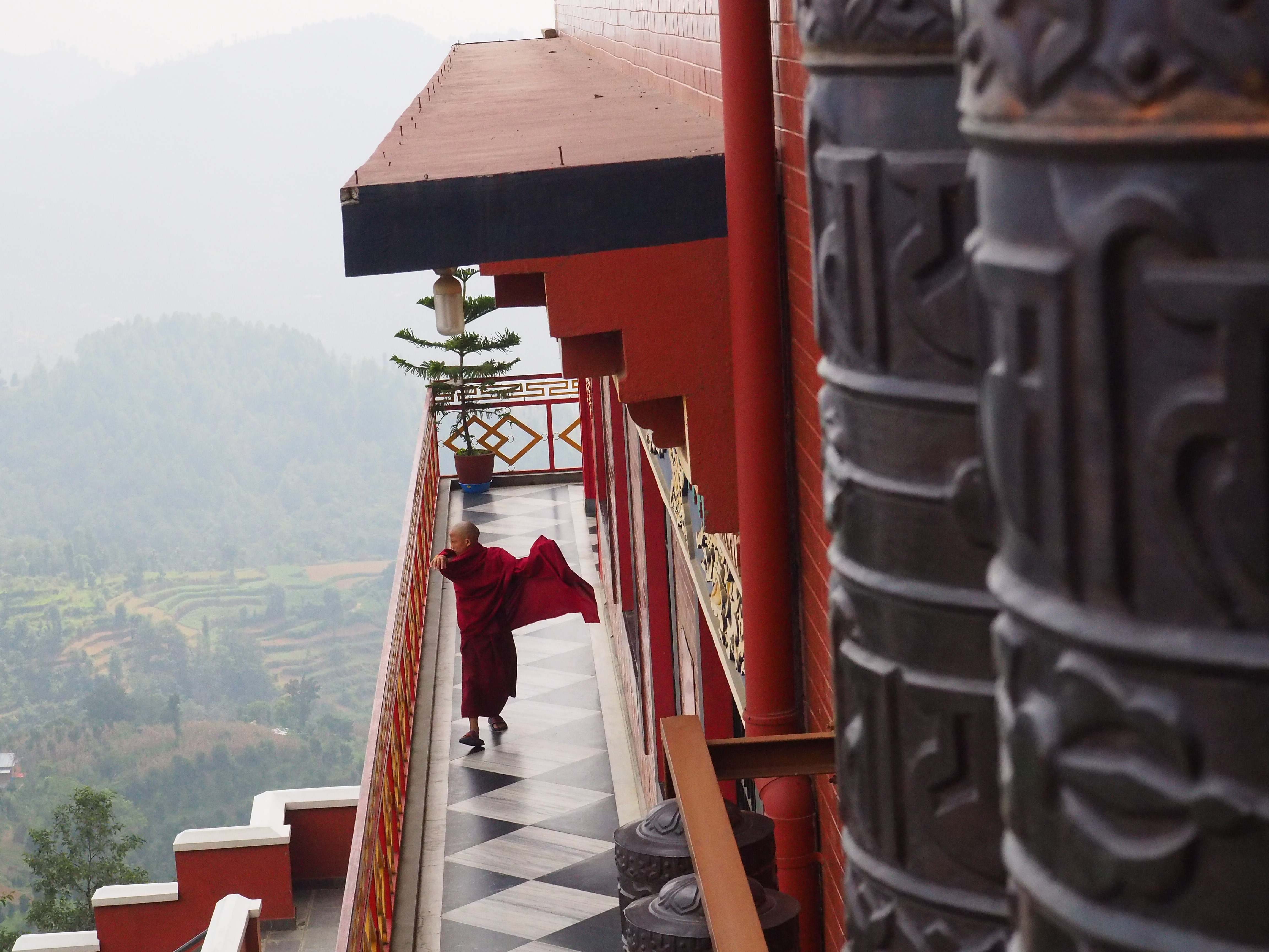 A young monk walking down a corridor fixing his robe